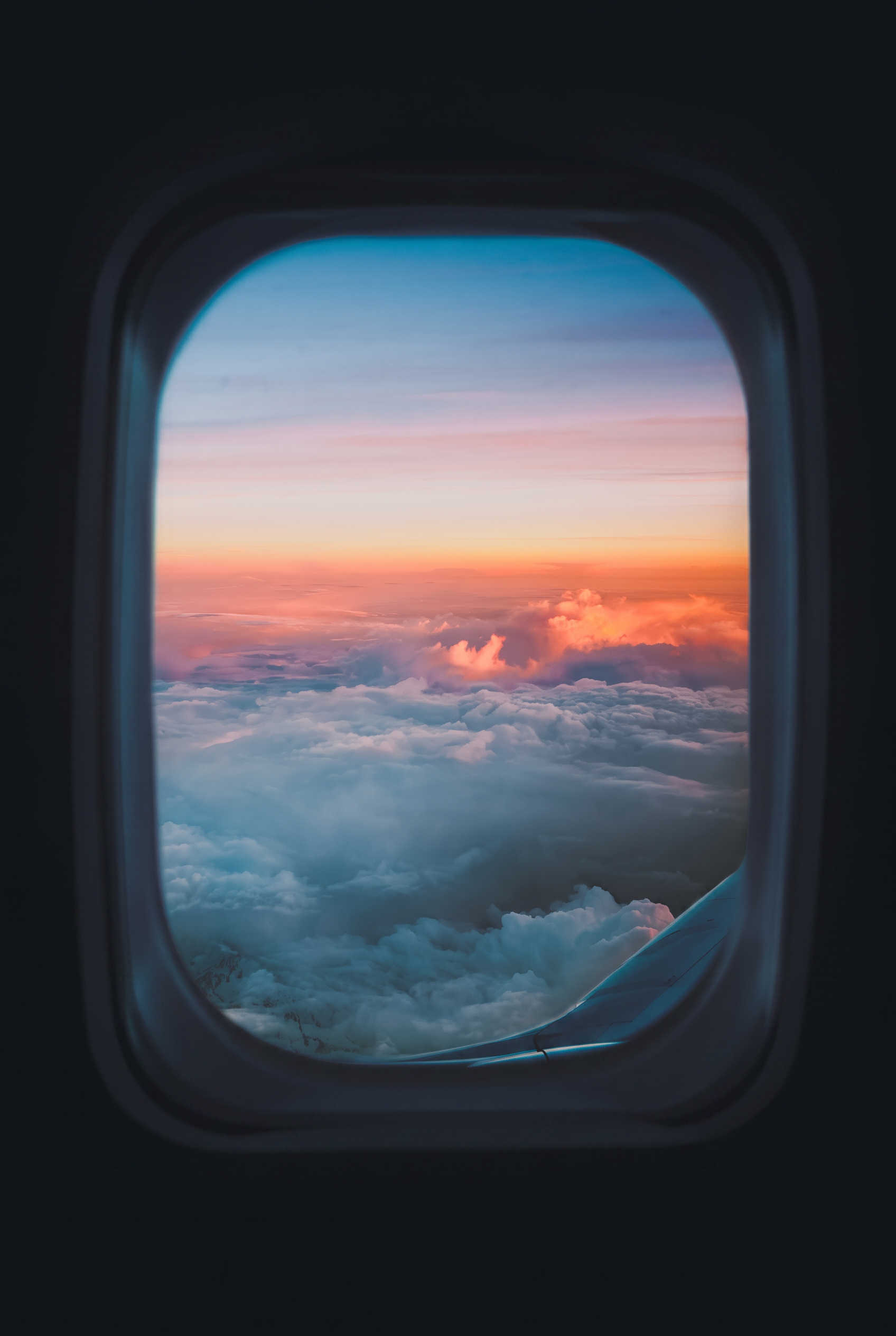 Uitzicht op wolken door een vliegtuigraam bij zonsondergang