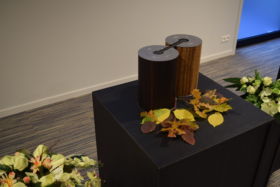 Twee houten urnen met herfstbladeren op een donkere sokkel