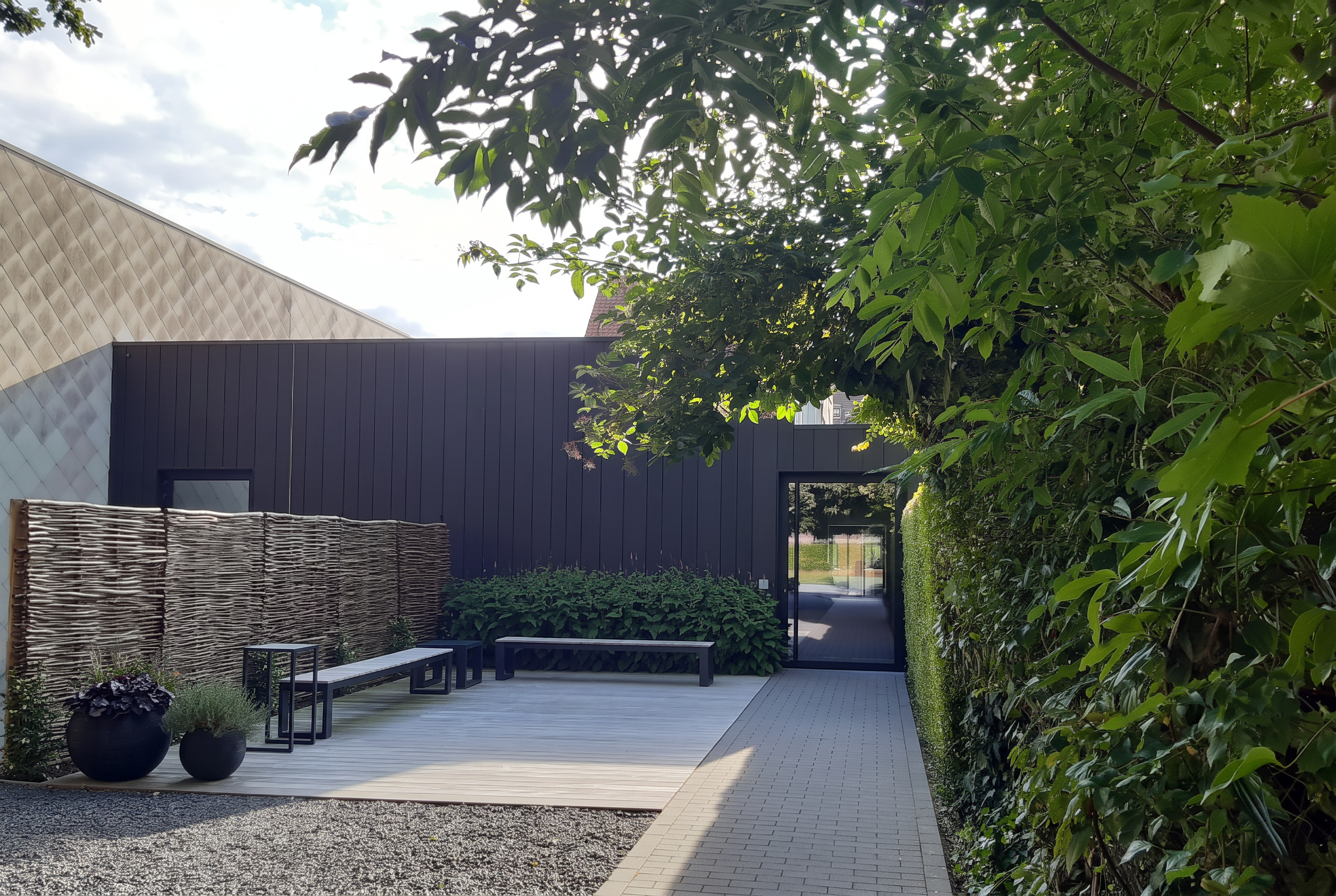 Buitenkant van het funerarium met terras, zitbanken en groen