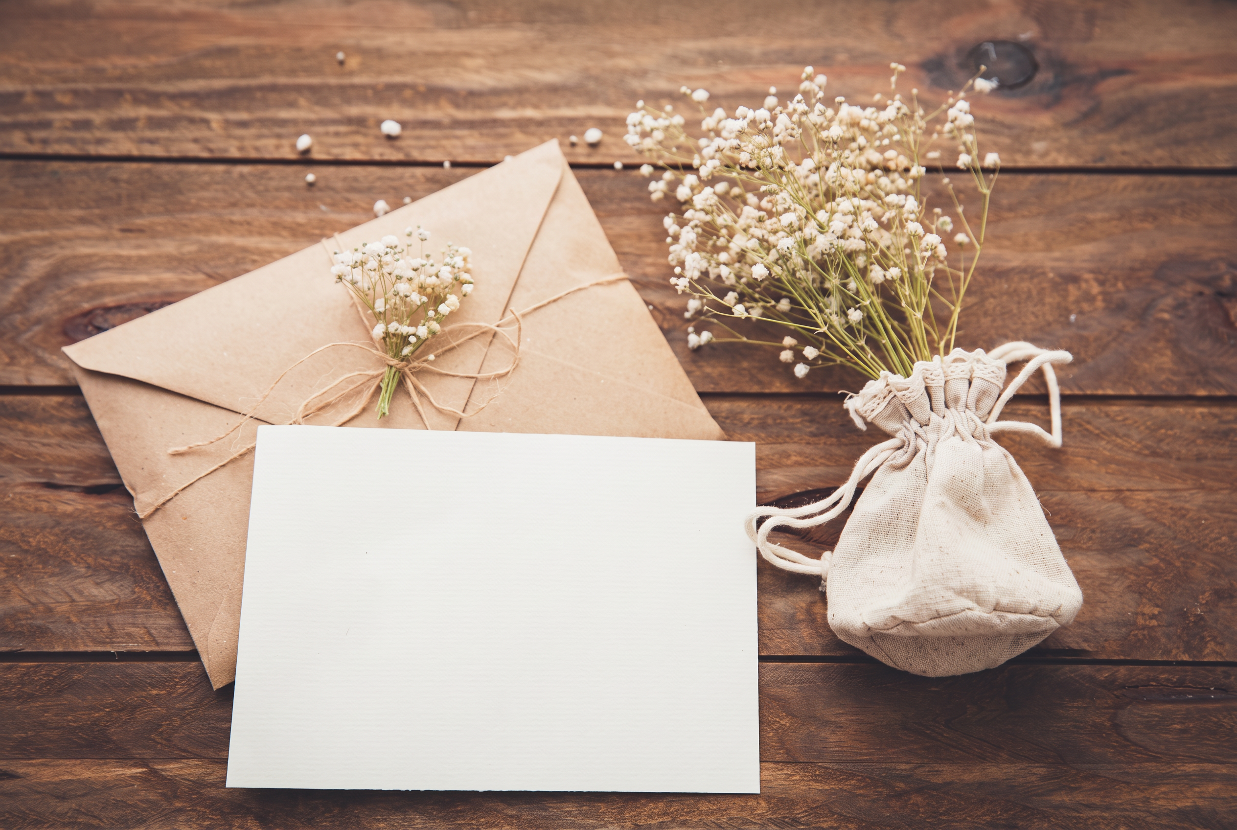 Rouwkaart, envelop en droogbloemen op een houten tafel